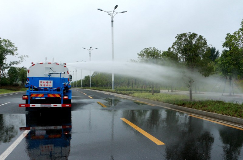 東風(fēng)灑水車正在噴灑路邊的花草